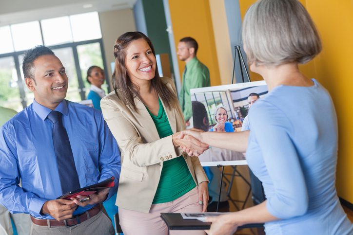 Woman shaking hands with professional executive at job fair event